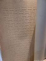 Close-up photo of beige Pehlavi rug showing raised basketweave geometric pattern texture.