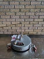 Top view of round surface cleaner on metal table with brick wall background
