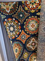 Photo showing corner of the Shaw Living area rug with multicolored detailed medallion floral and geometric patterns on dark navy blue background.