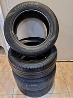 Stack of four tires showing sidewalls with “Cooper” and “CS5 Grand Touring” branding