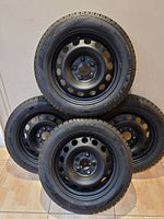 Four steel rims stacked in pyramid, showing front view of two rims against wall.