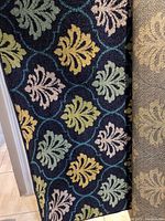 Close-up photo showing rug pattern with multicolored leaves and lattice design.