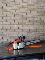 Side view of Stihl 032 AV chainsaw with guide bar and orange protective cover