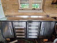 Front view showing eight drawers flanked by two cabinet doors under a stainless steel worktop