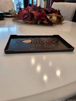 Side profile showing rectangular lacquer tray with textured surface and subtle red trim.