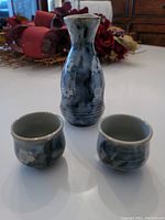 Front view of sake bottle and two cups showing dark blue ceramic with white cherry blossom patterns, all in excellent condition.