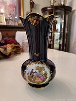 Front view of the vase showing the Fragonard style painting of couples and gold floral accents