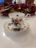 Side view of teacup and saucer showing colorful floral design and gold trim