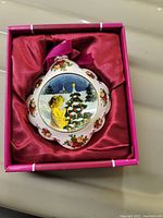 Top view of the Royal Albert Old Country Roses ornament in its original pink box with satin lining, showing the angel by the Christmas tree design.