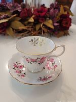 Tea cup and saucer set showing floral pattern, gold edges, and "Mother" gold inscription inside the cup rim with floral background.