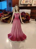 Front view of Royal Doulton July Ruby Lady Figurine showing pink to ruby gradient strapless gown and hairstyle.
