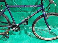 Side view of blue Specialized Rockhopper bicycle frame with drivetrain and rear wheel visible.