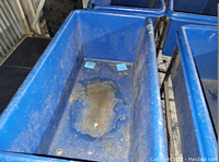 Close-up photo of the interior of the blue plastic basket truck showing dirt and wear inside the bucket