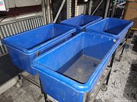 View of the blue plastic basket truck showing its size, rectangular shape and caster wheels.