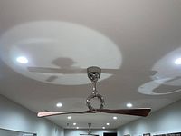 Photo showing one modern ceiling fan mounted on ceiling with chrome motor housing and two wooden blades.