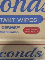 Close-up of box label showing disinfectant wipes information: brand name 'Seconds', 50 pcs per bag, 24 packs per carton.
