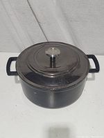 Top-down photo showing dark gray enamel Dutch oven with lid and metal knob, visible surface marks.