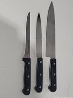 Three Zwilling J.A. Henckels kitchen knives with black handles arranged side by side showing front blade and handle.