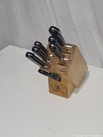 Angle of J.A. Henckles knife block holding six knives, showing hand-held knife grips and block top slots.