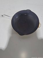 Photo showing the interior and handle of the small cream-colored skillet, visible signs of use and residue.