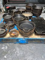 Top view of pallet loaded with various Lodge cast iron skillets and pans