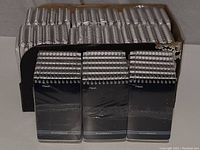 Box containing many handheld spiral-bound notepads with black covers, neatly stacked in rows.