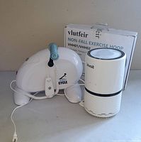 Easy Cycle stationary pedal exerciser, Vlutfeir magnetic exercise hoop box, and Levoit air purifier all visible on table surface.