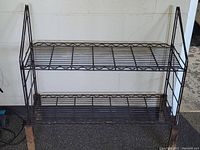 Full view of the brown steel wire shelf with two tiers and wooden legs.