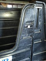 Side view of the tall black utility cart showing molded handles and side slots with wear marks.