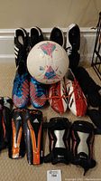 Four pairs of men's soccer shoes with an Adidas soccer ball in front and shin pads.