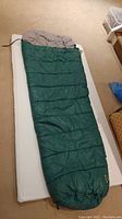 Full view of the green sleeping bag laid out on top of the mattress pad showing its size and condition.