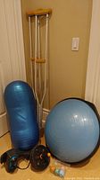 Photo showing BOSU ball, roller ball, ab roller, massage device, crutches, and yoga dice together.