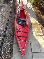 Red Necky Manitou Sport kayak on stone patio, showing sit-in cockpit and deck rigging