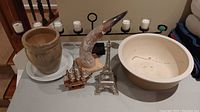 Full lot showing all seven items on table: large metal candle holder, ceramic planter with saucer, large ceramic bowl, model ship, Eiffel Tower sculpture, ceramic vase, faux carved horn.