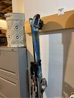 Rossignol Zenith skis and Kerma poles hanging vertically against a wall, showing full length and some details of bindings and grips.