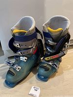 Front and side view of pair of blue Salomon men's downhill ski boots size 9.5 showing buckles and shell details.