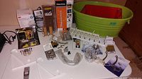 Overview of all items including boxed Bird B Gone enviro spike, 4x10 register cover, plastic bins in green and red, various hardware and hooks
