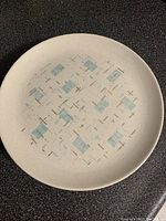 Single plate showing the speckled off-white background with light blue rectangles and brown crosses in the retro pattern.