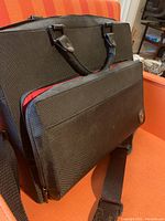 Black HEYS computer bag shown closed with front zippered compartment and handle details.