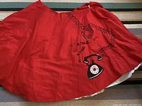 Full view of red circle skirt showing large vintage telephone graphic and pinned waistband