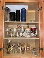 Shelf with plastic drink containers, insulated tumblers, and a small glass jar.