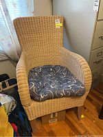 Front view of light wicker chair with blue floral cushion, showing texture and condition.