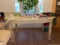 Front and side view of the wooden dining table with some items on it and two matching padded chairs visible.
