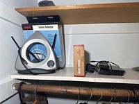 Photo showing RCA indoor antenna with two black antennas, alongside the boxed Wembley grill apron and a black alarm clock and phone handset base unit.
