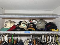 Shelf of 10 sports hats arranged in two rows with various logos including Boston Celtics, CAT Racing, and Boston Red Sox.