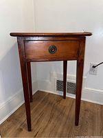 Front view of the wood side table showing drawer with round metal pull.