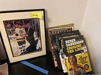 Framed signed hockey photo with hockey books stacked next to it.
