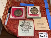 Three sterling silver Christmas ornaments displayed with original boxes and certificates: MOMA snowflake, two Towle medallions.