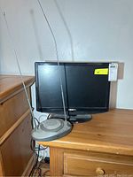 Photo shows Insignia 19-inch flat-screen TV on wooden stand with vintage gray tabletop TV antenna with two metal telescoping rods in front.