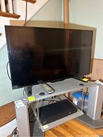 Frontal view of Insignia flat screen TV on stand, showing remote on top and Samsung DVD player below.